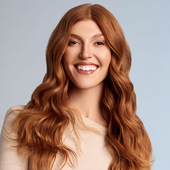 Woman with smooth, shiny copper hair styled in loose waves