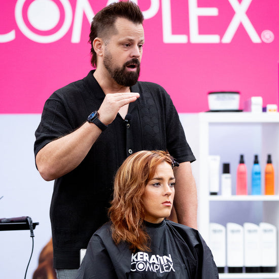 Keratin Complex educator demonstrating professional hair styling techniques during training
