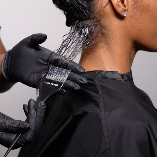 Stylist applying Keratin Complex smoothing treatment during professional training